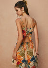 Woman wearing a colorful floral dress against a beige background