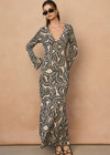 Woman wearing a long, patterned dress against a beige background