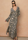 Woman wearing a long, patterned dress against a beige background