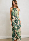 Woman wearing a tropical leaf patterned dress against a plain background