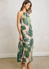 Woman wearing a tropical leaf patterned dress against a plain background