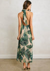 Woman wearing a tropical leaf patterned dress against a plain background