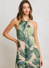 Woman wearing a tropical leaf patterned dress on a plain background