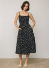 Woman wearing a black dress with white polka dots against a plain background