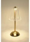 Gold table lamp with a clear glass shade on a beige background