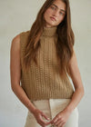 Woman wearing a beige knitted sleeveless sweater against a neutral background