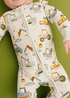 Baby wearing a onesie with construction vehicle patterns on a green background