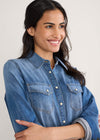 Woman wearing a blue denim shirt against a plain background