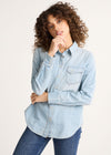 Woman wearing a light blue denim shirt and jeans on a white background