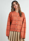 Woman wearing an orange striped sweater with buttons on a white background