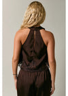 Woman wearing a brown halter top with lace details on a plain background