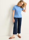Woman wearing a blue t-shirt and navy pants against a white background