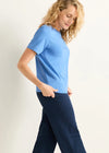 Woman wearing a light blue top and dark blue pants on a white background