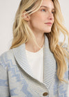 Woman wearing a patterned cardigan with a plain background