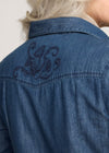 Blue denim shirt with embroidered design on the back, worn by a person.