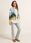 Woman wearing a colorful cardigan with a landscape pattern on a white background