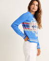 Woman wearing a blue sweater with a colorful pattern on a white background