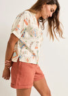 Woman wearing a patterned shirt and pink shorts on a white background