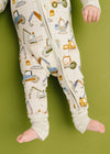 Child wearing pajama pants with construction vehicle pattern on a green background