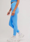 Person wearing bright blue leggings and a matching top on a light gray background