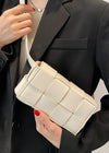 Person holding a white woven handbag with a black suit jacket
