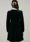 Green velvet dress with long sleeves on a plain background