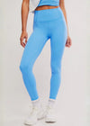 Person wearing blue leggings and white sneakers on a plain background