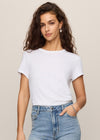 Woman wearing a white t-shirt and light blue jeans against a beige background