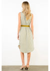 A woman stands with her back to the camera wearing a sleeveless midi dress with vertical stripes in beige and white, accented by a wide olive green belt, paired with beige high-heeled sandals.