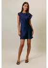 A woman modeling a navy blue satin mini dress with lace cap sleeves, standing against a plain beige studio background.