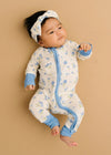 Baby wearing a floral onesie with blue accents on a beige background