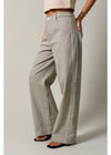 A person wearing high-waisted, wide-leg trousers in a beige and black gingham check pattern, styled with black slide sandals against a neutral studio background.