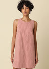 Woman wearing a pink striped dress against a beige background