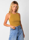 Woman wearing a mustard yellow tank top and blue jeans on a white background