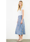 Woman wearing a blue floral skirt and white top on a plain background