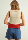Person wearing a red and beige sleeveless top with denim shorts on a plain background