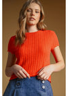Woman wearing a red knitted top against a brown background