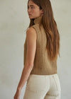 Woman wearing a beige knitted vest against a plain background