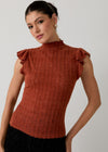 Woman wearing a rust-colored ribbed top with ruffled shoulders against a plain background