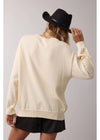Person wearing a cream sweater and black hat on a plain background