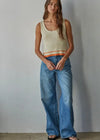 Woman wearing a sleeveless ribbed top and blue jeans against a plain background