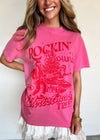 Person wearing a pink t-shirt with red graphic design and text.