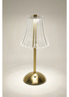 Table lamp with a clear glass shade and gold base on a neutral background