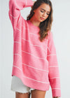 Woman wearing a pink sweater with white stripes on a plain background