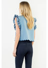 A woman shown from the back wearing a light blue sleeveless top with ruffled sleeves and a scalloped hem, paired with dark blue jeans, against a plain white background.