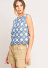 Woman wearing a blue patterned top and beige shorts on a plain background