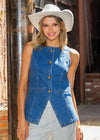Woman wearing a denim vest and white cowboy hat against a brick wall.