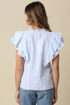 Woman wearing a blue and white striped top with ruffled sleeves on a beige background