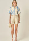Woman wearing a striped shirt and beige shorts with a neutral background
