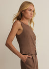 Woman wearing a brown sleeveless top and pants against a beige background